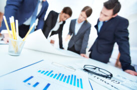 Business,Objects,On,Background,Of,Engineers,Discussing,Blueprint,At,Meeting